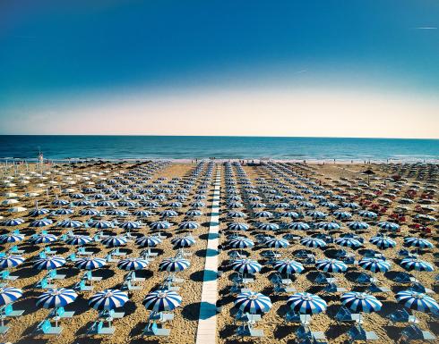 Beach with blue and white umbrellas aligned, sea view.